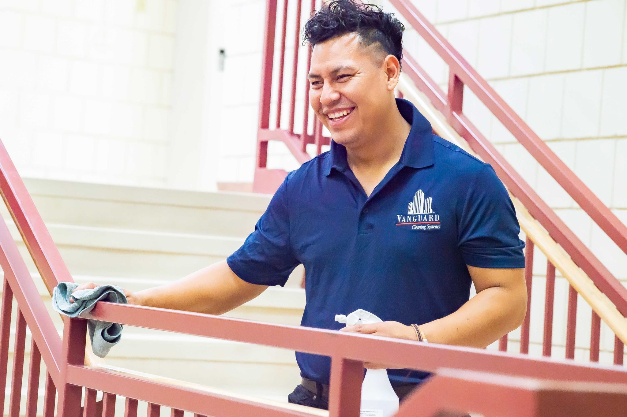 Vanguard cleaning systems employee smiling while working and cleaning a railing