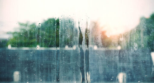 Close-up of hard water stains and mineral buildup on a commercial glass window — example of issues addressed in commercial window cleaning tips.